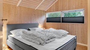 A bedroom with a bed, wooden walls, a window with blinds, and a nightstand with a lamp. - Awesome home in Oksbøl with sauna (Oksbøl)