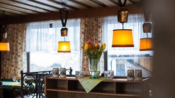 Un comptoir d’accueil en bois, agrémenté d’un vase de tulipes, de lampes suspendues et offrant une vue sur les montagnes par la fenêtre.