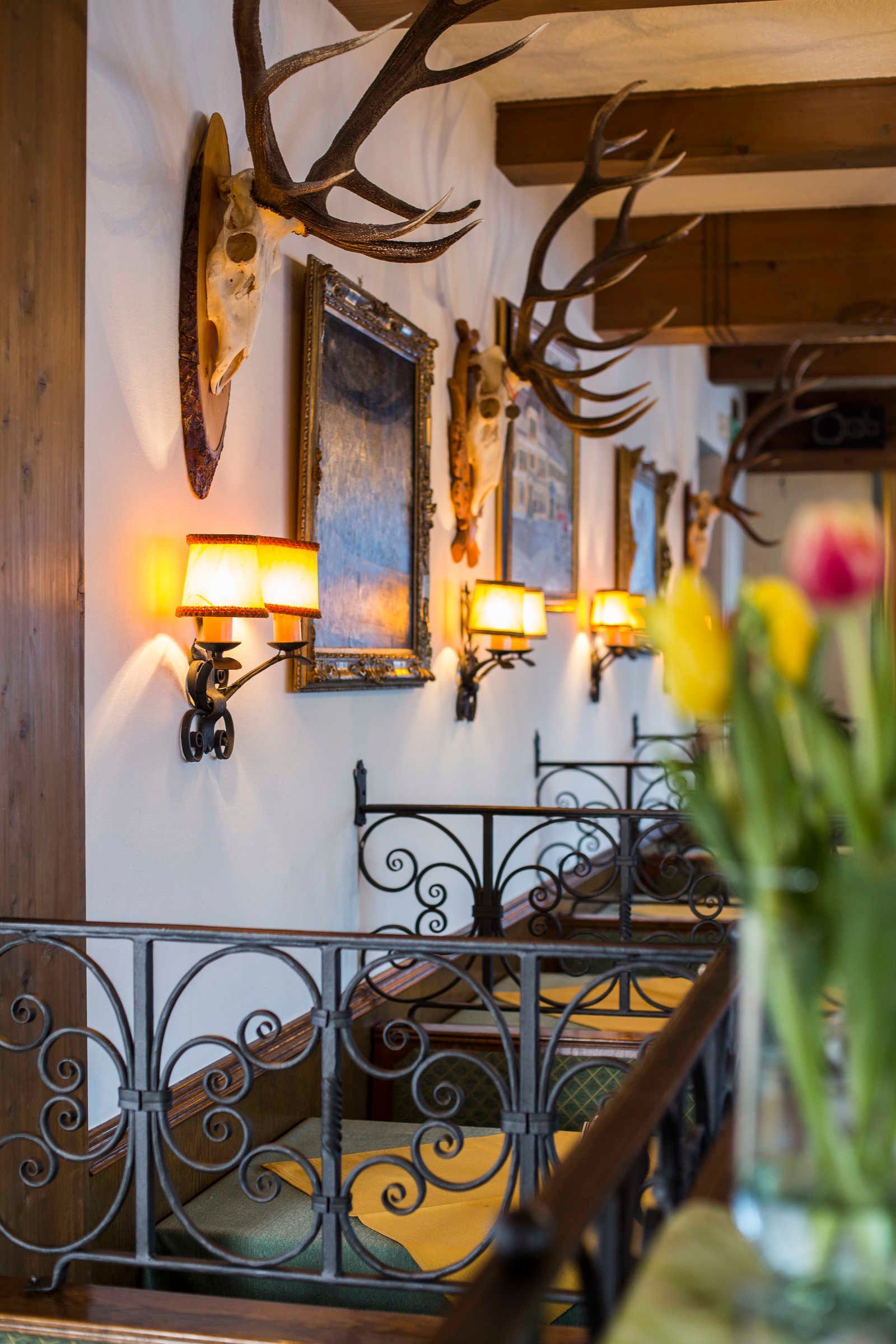 A room with wall-mounted lamps, antler decorations, and a metal railing.