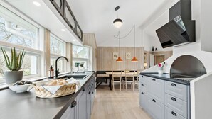 Une cuisine moderne dotée d’un îlot central, d’un plancher en bois et d’un coin repas avec une table et des chaises en bois.