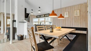 Une cuisine moderne dotée d’un îlot central, d’une table à manger en bois et de luminaires suspendus.