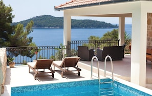 A poolside area with lounge chairs, a pool, and a view of the sea. - Lovely home in Prizba (Prizba)