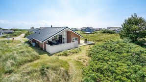 Ett modernt hus med ett sluttande tak, ett garage och en uteplats med utemöbler.