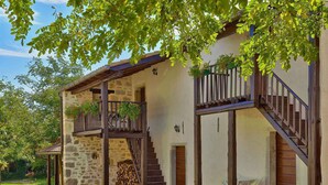 A rustic stone building with a wooden staircase, a balcony with hanging plants, and a stone wall. - Holiday home with terrace and barbecue (Buzet)
