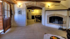 A rustic interior with exposed wooden beams, a stone fireplace, and a dining area visible through an archway. - Holiday home with terrace and barbecue (Buzet)