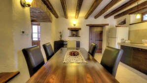 A dining area with a wooden table and chairs, a decorative centerpiece, and a kitchen in the background. - Holiday home with terrace and barbecue (Buzet)
