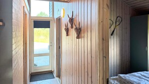 Una habitación con paredes de madera, una cama y una puerta que da al exterior.