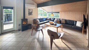 Una sala de estar acogedora con un amplio sofá modular, una mesa de centro de madera y una chimenea.