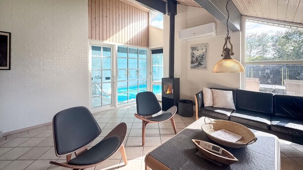 Un amplio espacio de estar con piscina, chimenea y un conjunto de asientos cómodo.