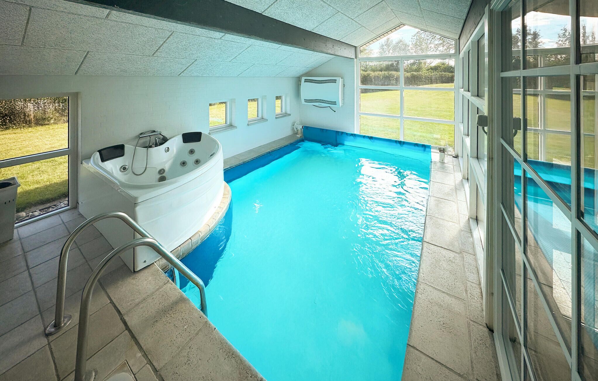 Une piscine avec un jacuzzi, une échelle et une vue sur l’extérieur.