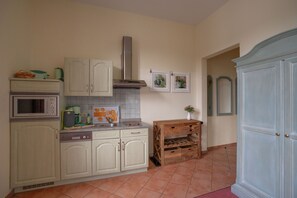 Una cocina con armarios blancos, un microondas, una estufa y una bodega de madera.