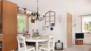 A kitchen with a round table, white chairs, wooden cabinets, a chandelier, and a window.