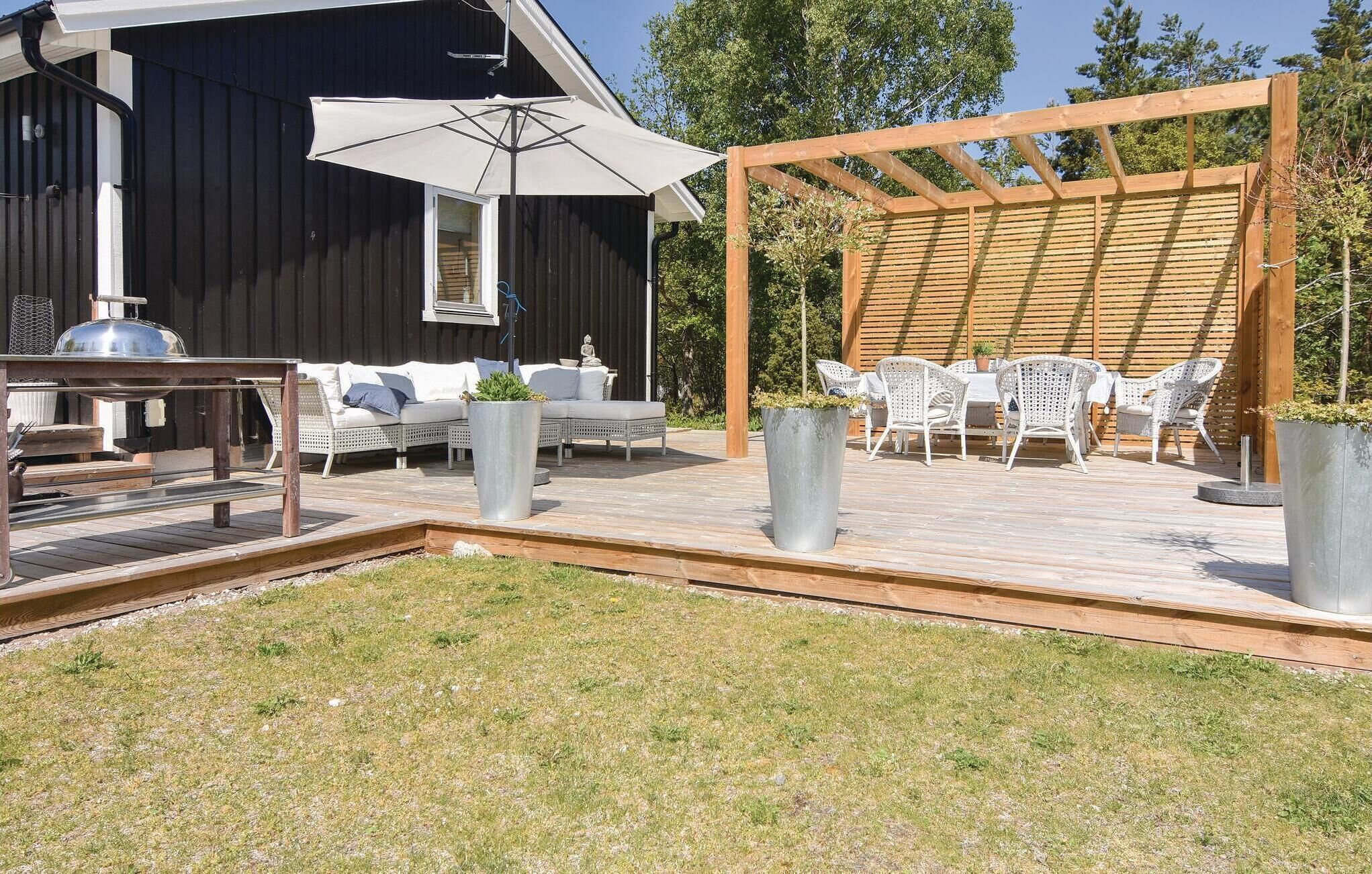Ein Patio im Freien mit einer Holz-Pergola, weißen Korbmöbeln und einem großen Sonnenschirm.