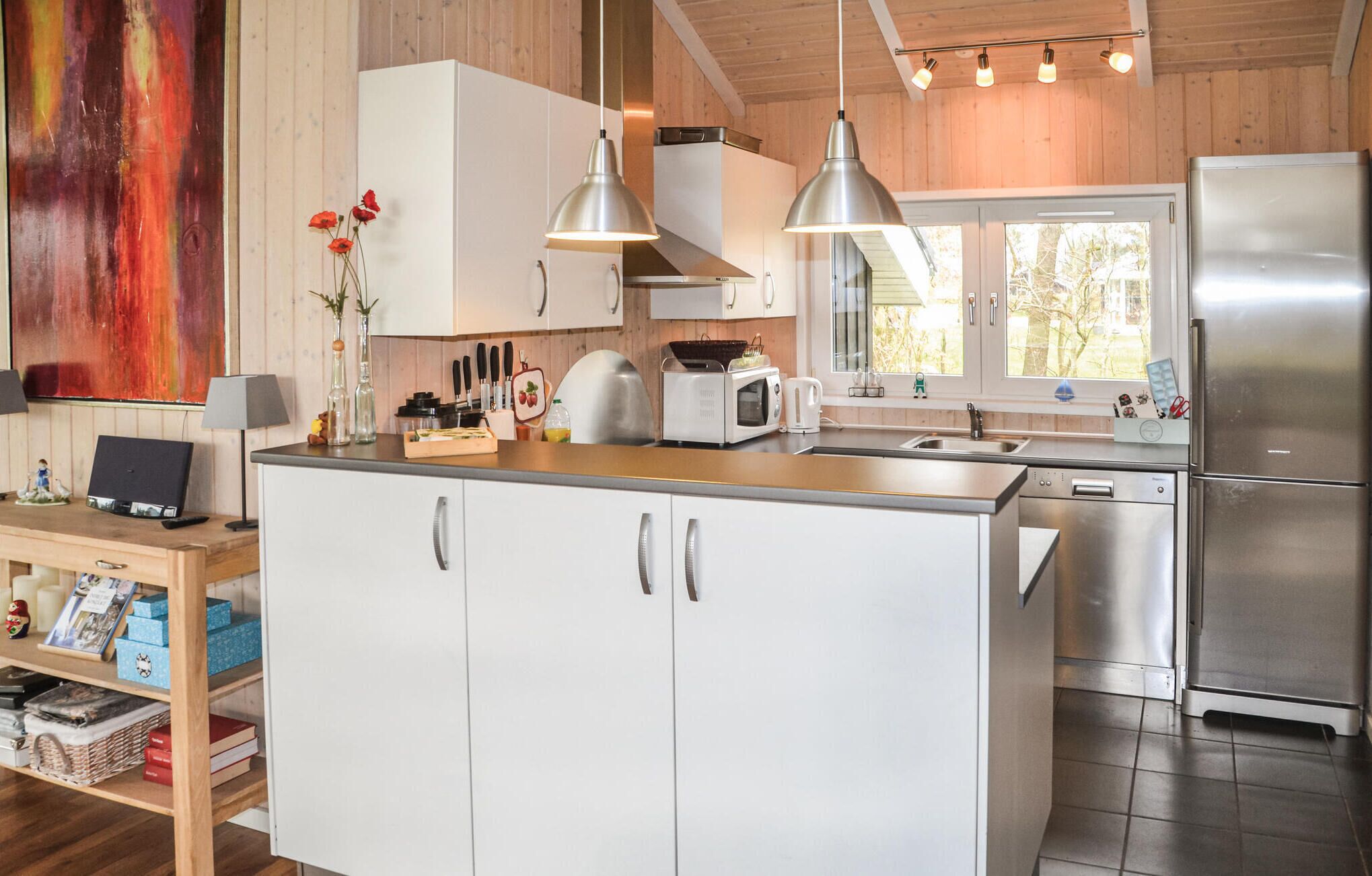 A modern kitchen with white cabinets, stainless steel appliances, and pendant lighting.