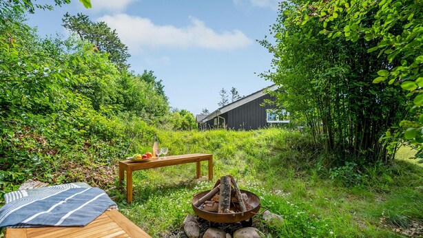 Eine Holzterrasse mit Feuerstelle und einem Tisch mit Früchten und Gläsern.