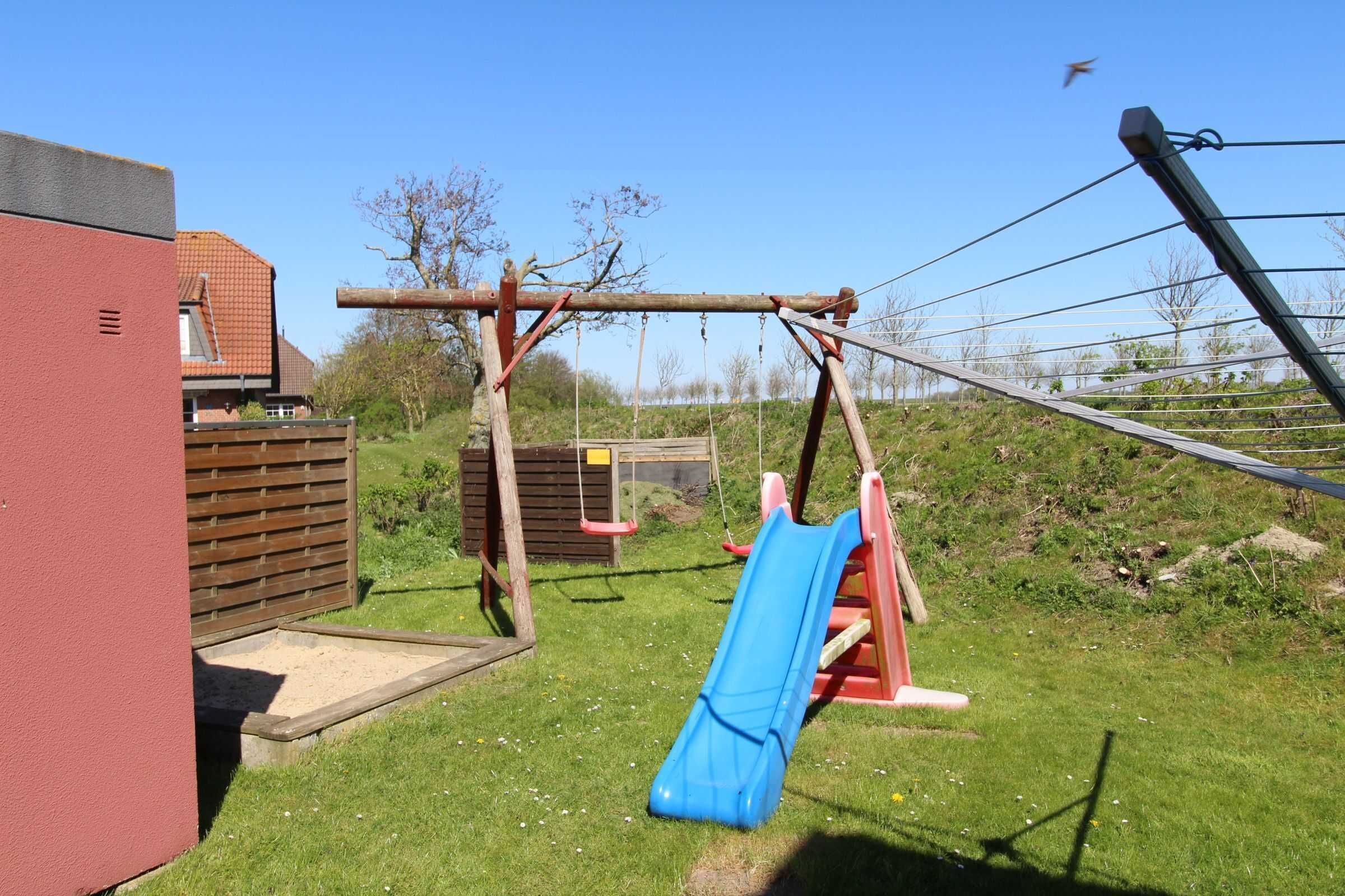 Ein Spielplatz mit einer blauen Rutsche und Schaukeln.