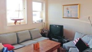 Una sala de estar con un sofá, un televisor y un cuadro en la pared.