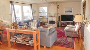 Una sala de estar acogedora con chimenea, televisor y una estantería llena de libros.
