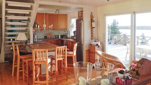 Una cocina moderna con armarios de madera, una isla central con sillas y vistas a un paisaje nevado a través de amplios ventanales.