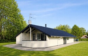 Ein modernes, eingeschossiges Haus mit geneigtem Dach, einer Satellitenschüssel und einem Schornstein.