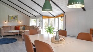 A modern living room with a sofa set, a dining table with chairs, and a large window providing natural light. - Nice home in Oksbøl with sauna (Oksbøl)