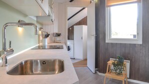 A modern kitchen with stainless steel sinks, a coffee machine, and a washing machine. - Nice home in Oksbøl with sauna (Oksbøl)