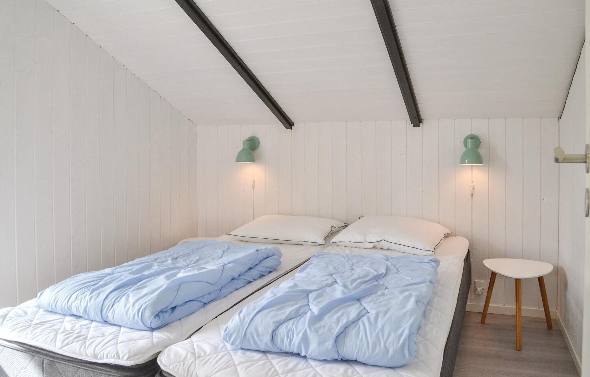 Ein Zimmer mit zwei Betten, jeweils mit einer blauen und weißen Tagesdecke, sowie einem kleinen weißen Tisch.
