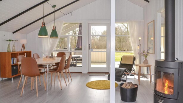A cozy interior with a dining area, a fireplace, and a view of the outdoors. - Nice home in Oksbøl with sauna (Oksbøl)