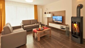 Una sala de estar moderna con sofá, mesa de centro, televisor, chimenea y ventana con cortinas.