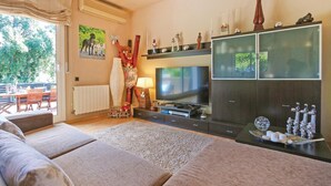 Un soggiorno con un divano, una televisione e un mobile contenitore con oggetti decorativi.