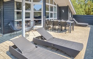 Ein Terrassenbereich im Freien mit Korlounge-Stühlen, einem Tisch und Stühlen.