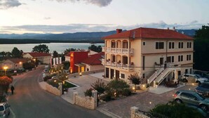 A two-story building with a balcony, a driveway, and a view of the sea. - Holiday apartment with balcony and sea view (Klimno)