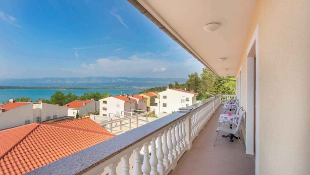 A balcony with a view of a coastal town, a tiled roof, and a railing. - Holiday apartment with balcony and sea view (Klimno)