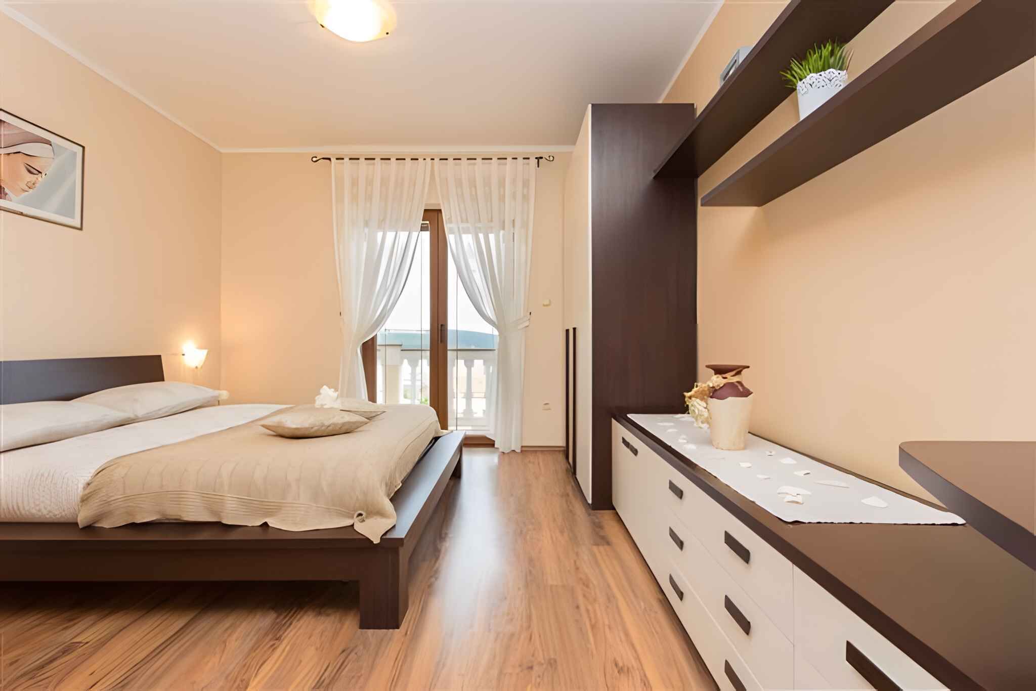 Ein Schlafzimmer mit einem Bett, Nachttischen, einer Kommode und einem Fenster mit Vorhängen.