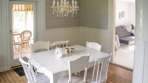 A dining area with a white table and chairs, a chandelier, and a view of a living room with a sofa. - 3 bedroom awesome home in Mårdaklev (Mårdaklev)