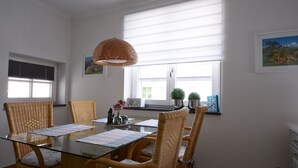 A dining area with a glass table, wicker chairs, and a hanging light fixture. - Apartment 1 - NEW! Rental Binz (Binz)