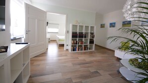 A room with a bookshelf, a white sofa, and a plant. - Apartment 1 - NEW! Rental Binz (Binz)