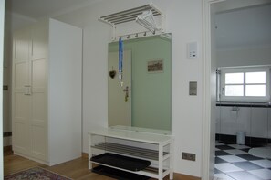 A room with a large mirror, a white wardrobe, a small table, and a bathroom with a checkered floor.