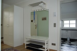 A room with a large mirror, a white wardrobe, a small table, and a bathroom with a checkered floor. - Apartment 1 - NEW! Rental Binz (Binz)