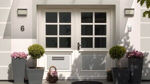 A white building with a double door, number 6, potted plants, and a small basket. - Apartment 1 - NEW! Rental Binz (Binz)