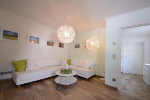 A living room with a white sofa, a round coffee table, and two spherical light fixtures.