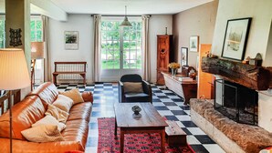 Una sala de estar con piso a cuadros, sofá de cuero, mesa de centro de madera y chimenea.