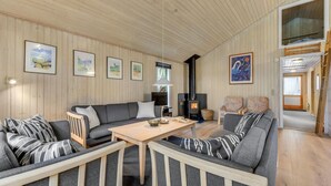 En hyggelig stue med sofa, lænestole, et træbord og en pejs.