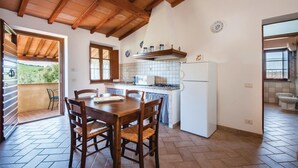 Een keuken met een eettafel, stoelen, een koelkast en een raam.