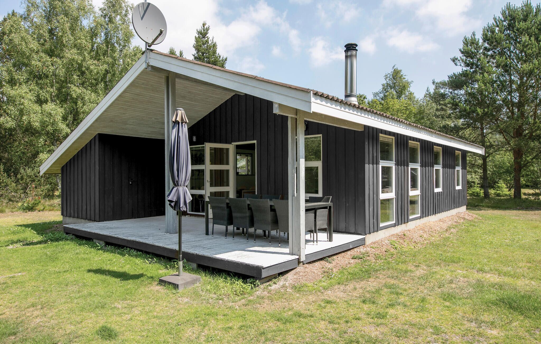 Uma cabana moderna com varanda coberta, chaminé e antena parabólica.