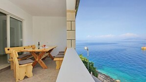 A balcony with a wooden table and chairs, a lamp, and a view of the sea. - 3 bedroom beach front apartment in Prigradica (Prigradica)