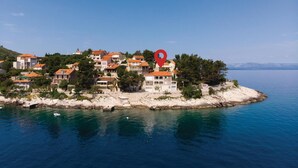 A coastal village with terraced houses, a clear blue sea, and a red location marker. - 3 bedroom beach front apartment in Prigradica (Prigradica)