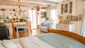A cozy room with a bed, a dining table, and a kitchen area.