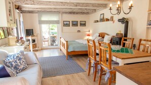 A cozy room with a bed, wooden furniture, a dining table, and a fireplace.