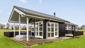 Une maison moderne dotée d’un patio couvert, de grandes fenêtres et d’une terrasse.